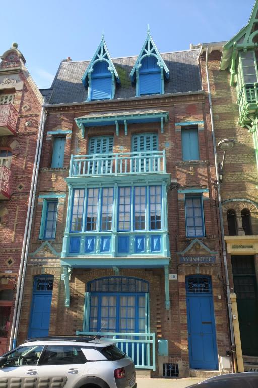 - un grand bâtiment en briques avec un balcon bleu dans l'établissement Villa Yvonnette, à Mers-les-Bains