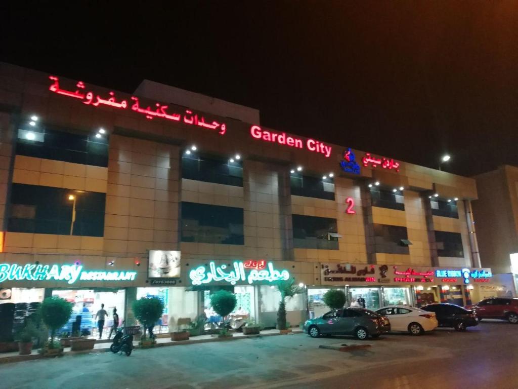 um edifício com carros estacionados em frente a ele à noite em Garden City 2 em Riade
