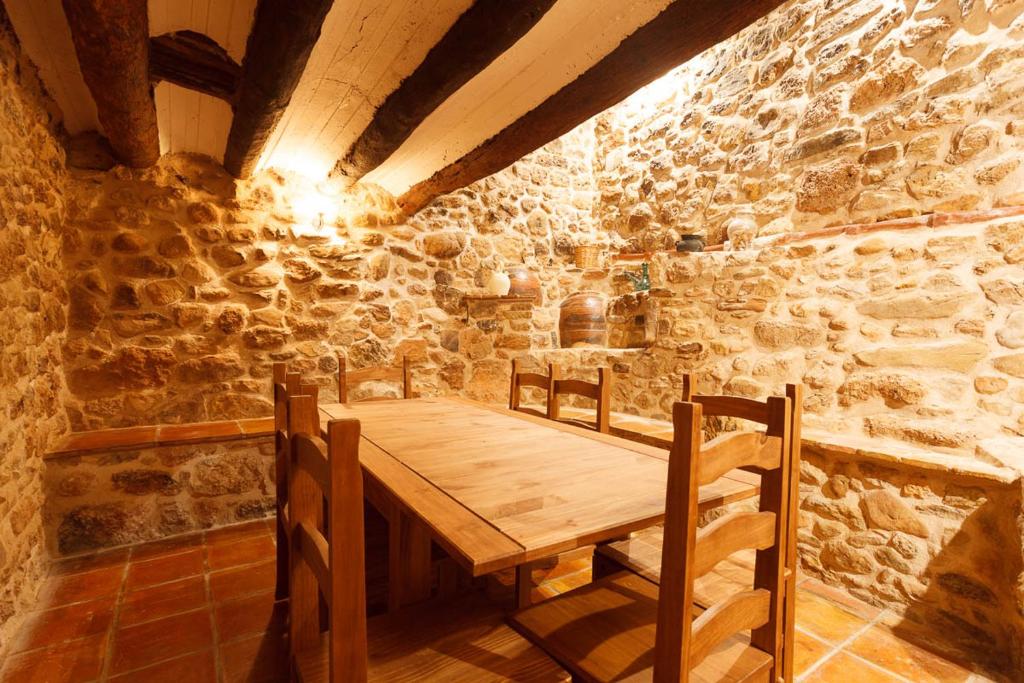 una mesa de madera en una habitación con una pared de piedra en Apartamentos La Pastora, en Peñarroya de Tastavins