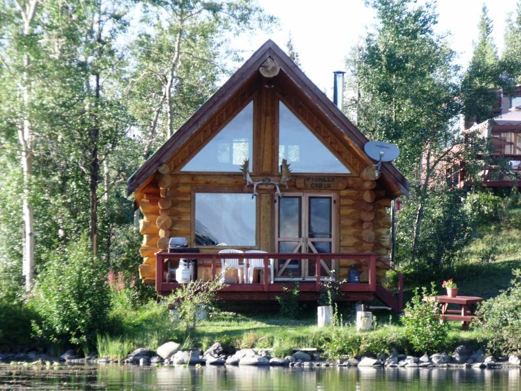 a log cabin by the water with a large window at Nimpo Lake Resort in Nimpo Lake