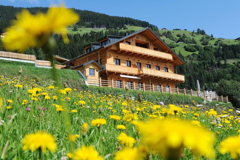 a house on a hill with a field of flowers at dolomit24 | design apARTments in Sillian
