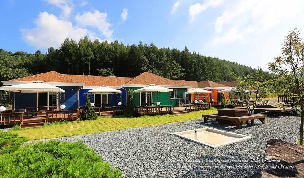 a row of houses with tables and benches in a yard at Rainbow Hwangto Pension in Pyeongchang