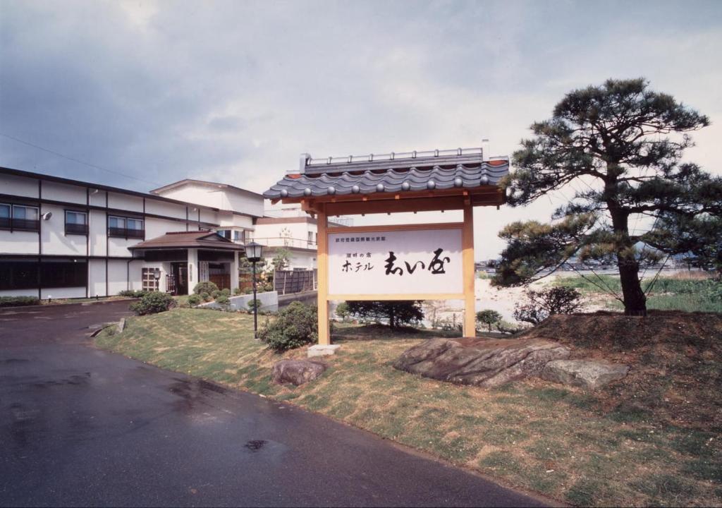 佐渡市的住宿－志屋日式旅館，一座有树的建筑前面的标志
