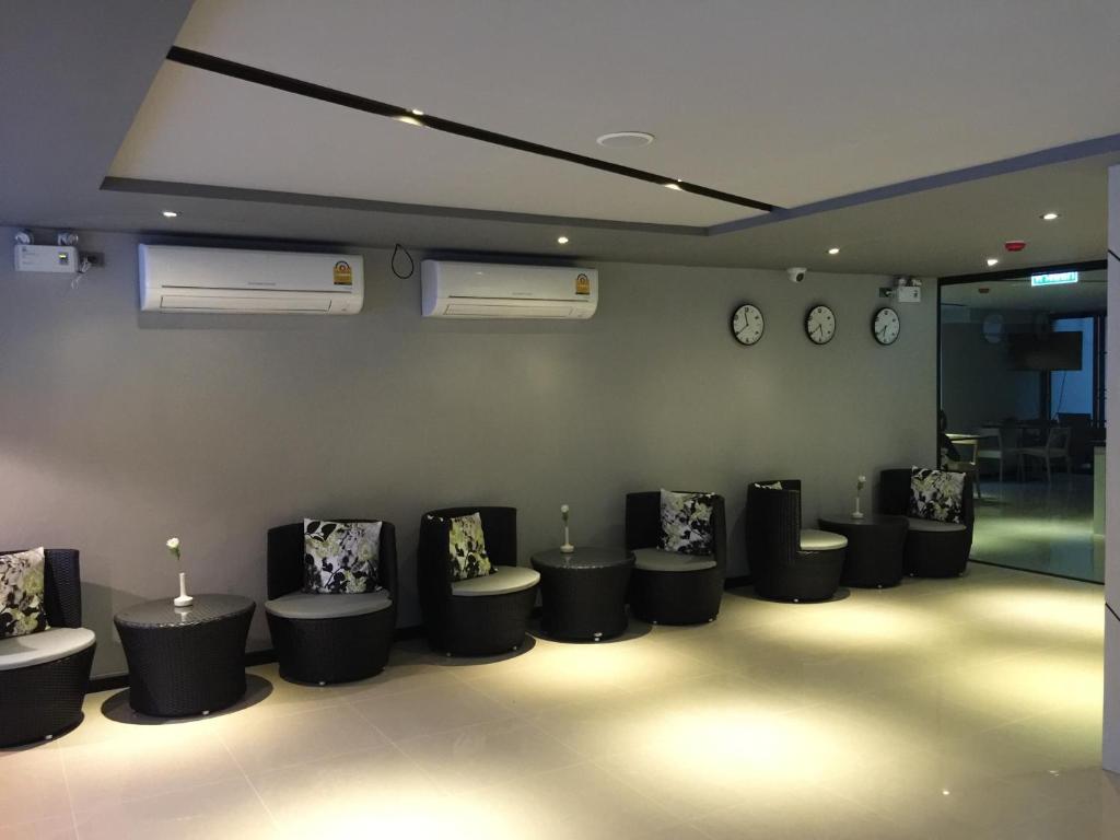A quiet lounge with individual upholstered chairs, side tables and multiple wall clocks.