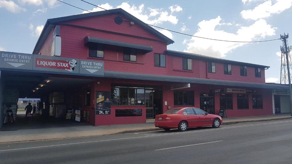 a red building with a red car parked in front of it at Sarina Hotel in Sarina