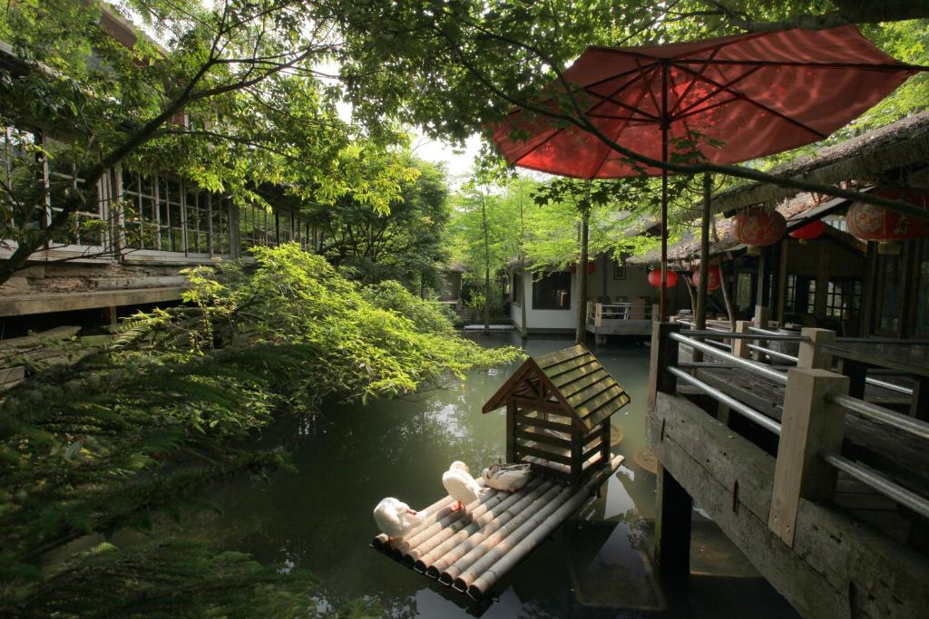 una persona sentada en un banco en un río con un paraguas en Zhou Ye Cottage, en Sanyi