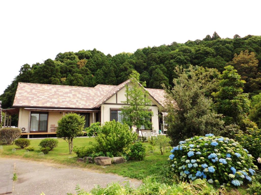 una casa al lado de una colina con árboles en Minshuku Hoshi no Sumika, en Shibushi