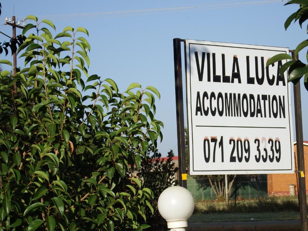 a sign that reads villa lobby association next to a bush at Villa Luca Guesthouse & Chalets in Swartruggens