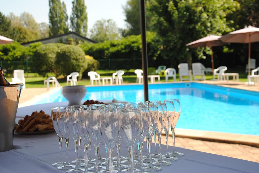 un grupo de copas de vino sentado en una mesa junto a una piscina en Logis Le Relais Fleuri, en Sauvigny-le-Bois