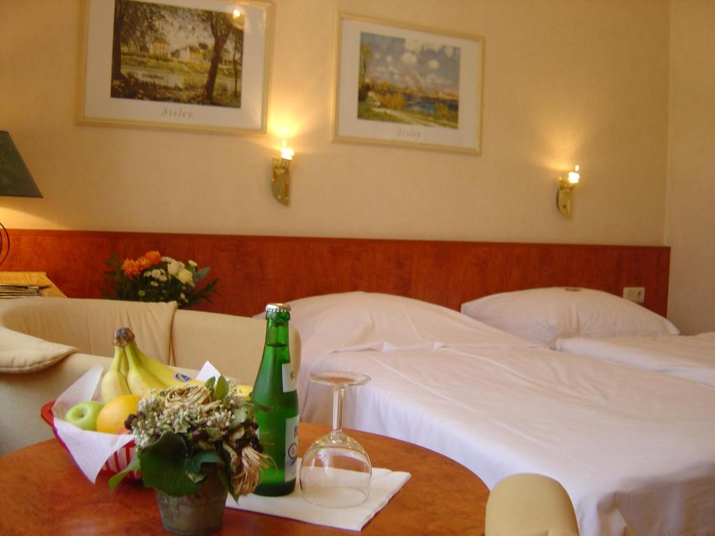 a hotel room with a bed and a table with a bowl of fruit at Bahnhof-Hotel Saarlouis in Saarlouis