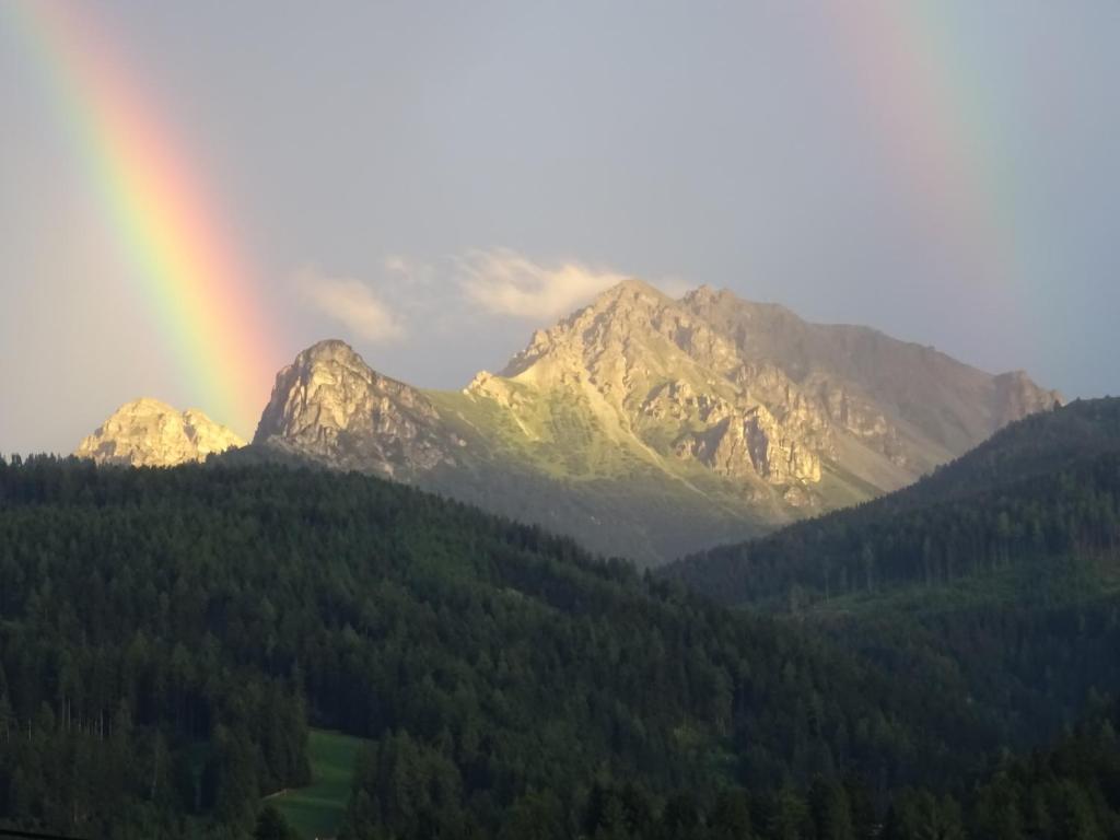 a rainbow in front of a mountain with trees at Ferienwohnung Traudl Singer in Innsbruck