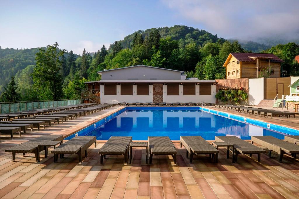 a large swimming pool with chairs and a building at Stanislavsky Hotel Group in Yaremche