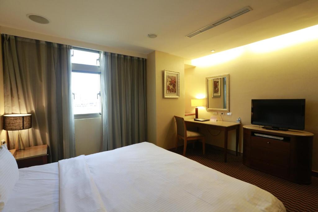 a hotel room with a bed and a desk with a television at Jingan Classic Inn in Zhonghe