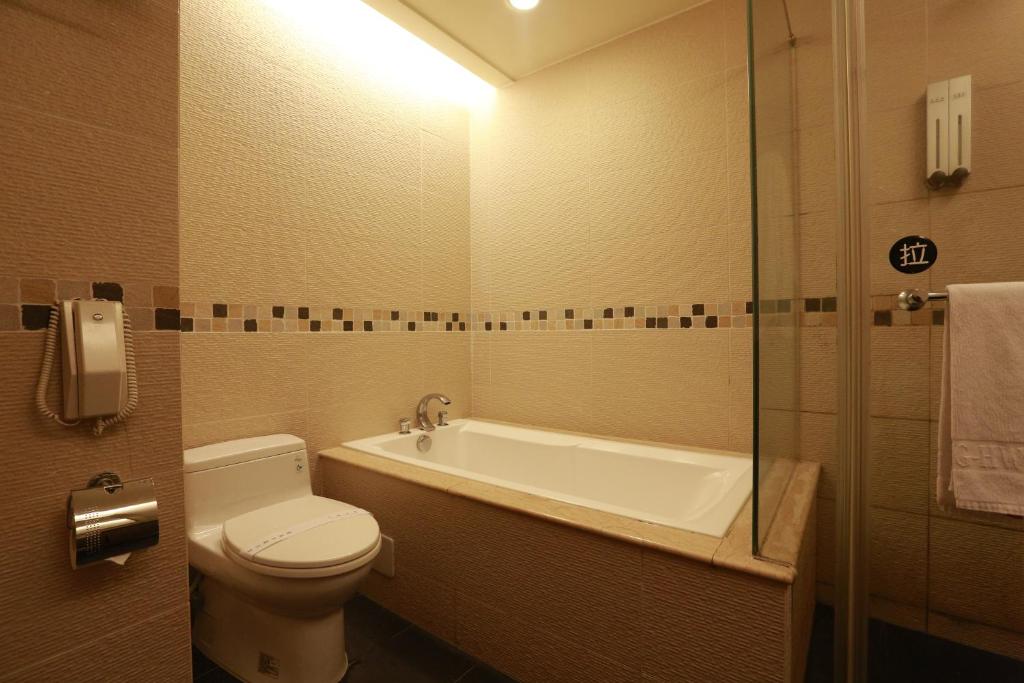 a bathroom with a toilet and a tub and a sink at Jingan Classic Inn in Zhonghe