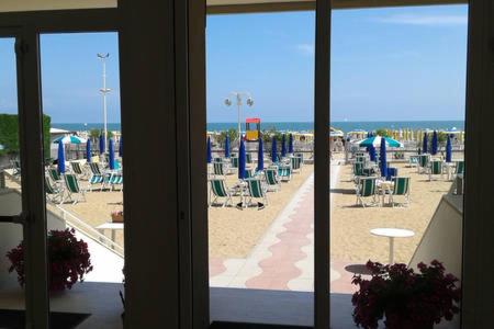 vista su una spiaggia con sedie e ombrelloni di Appartamento Centromare solo famiglie a Lido di Jesolo
