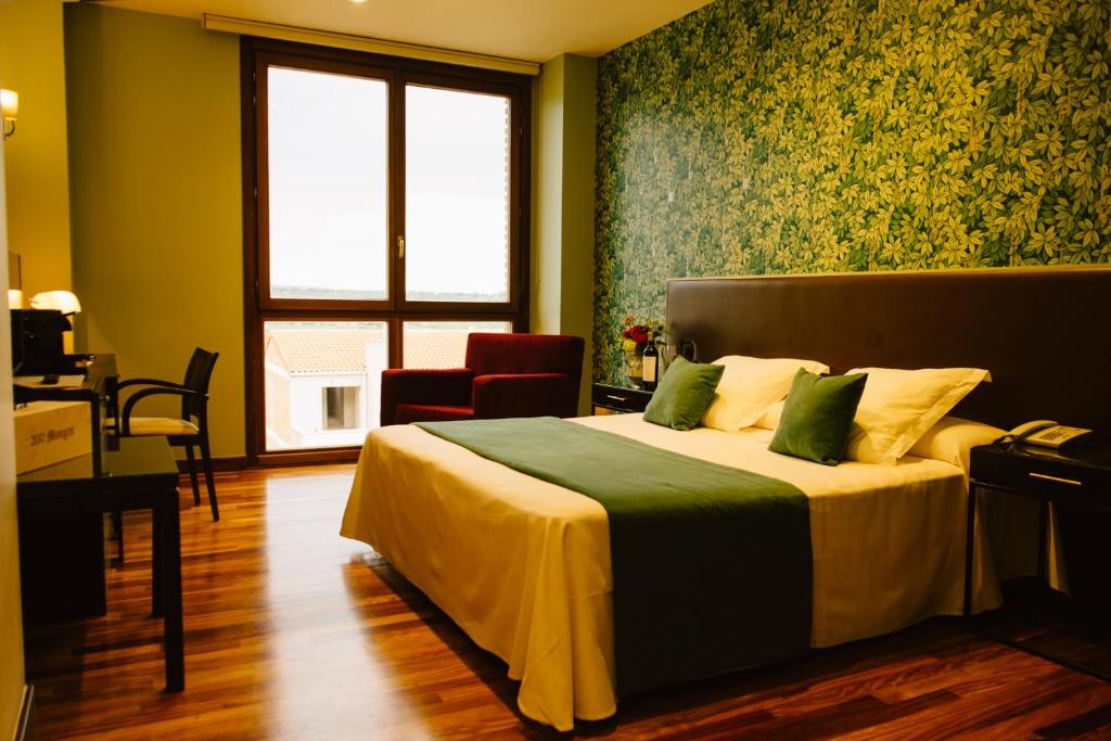Un dormitorio con una cama y un escritorio y una ventana. en Hotel Vinícola Real-200 Monges, en Albelda de Iregua