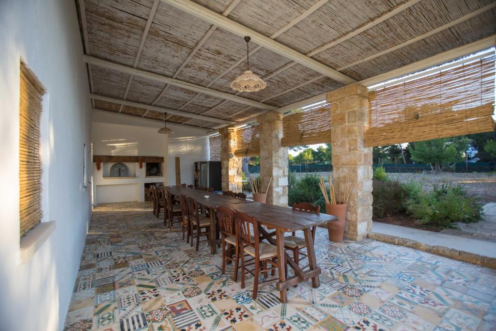 eine große Terrasse mit einem langen Tisch und Stühlen in der Unterkunft Santa Marina Masseria del Salento in Gallipoli