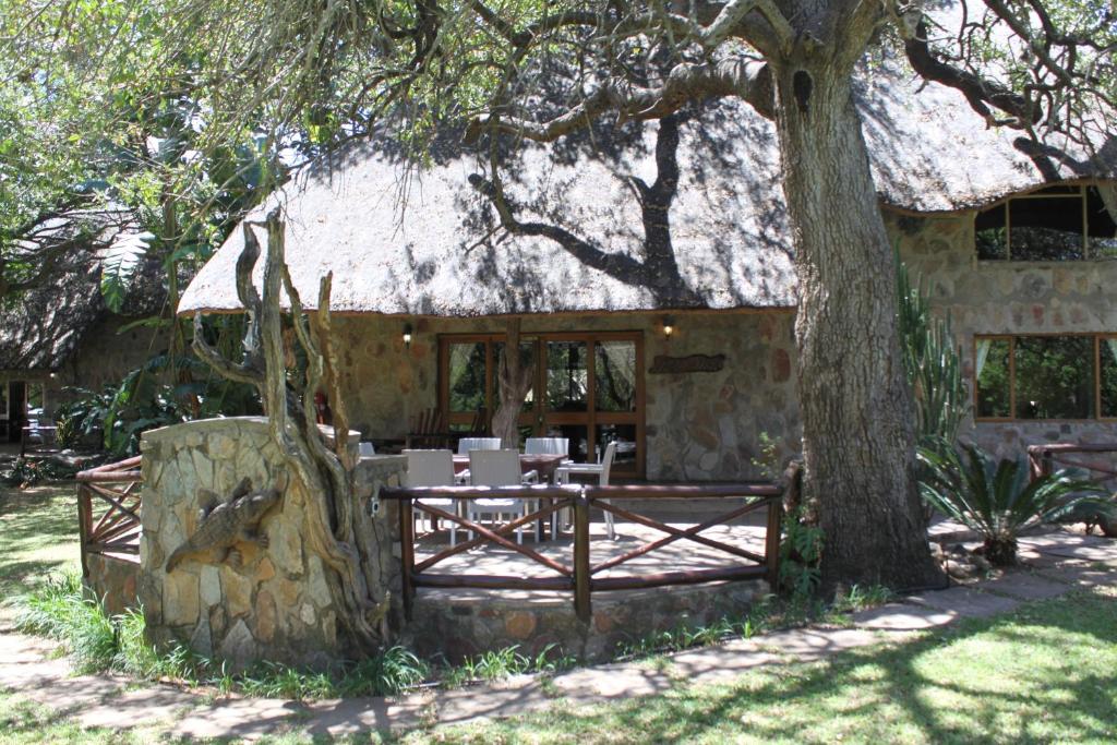 une maison en pierre avec une table et des chaises sous un arbre dans l'établissement Moholoholo Ya Mati, à Kampersrus AH