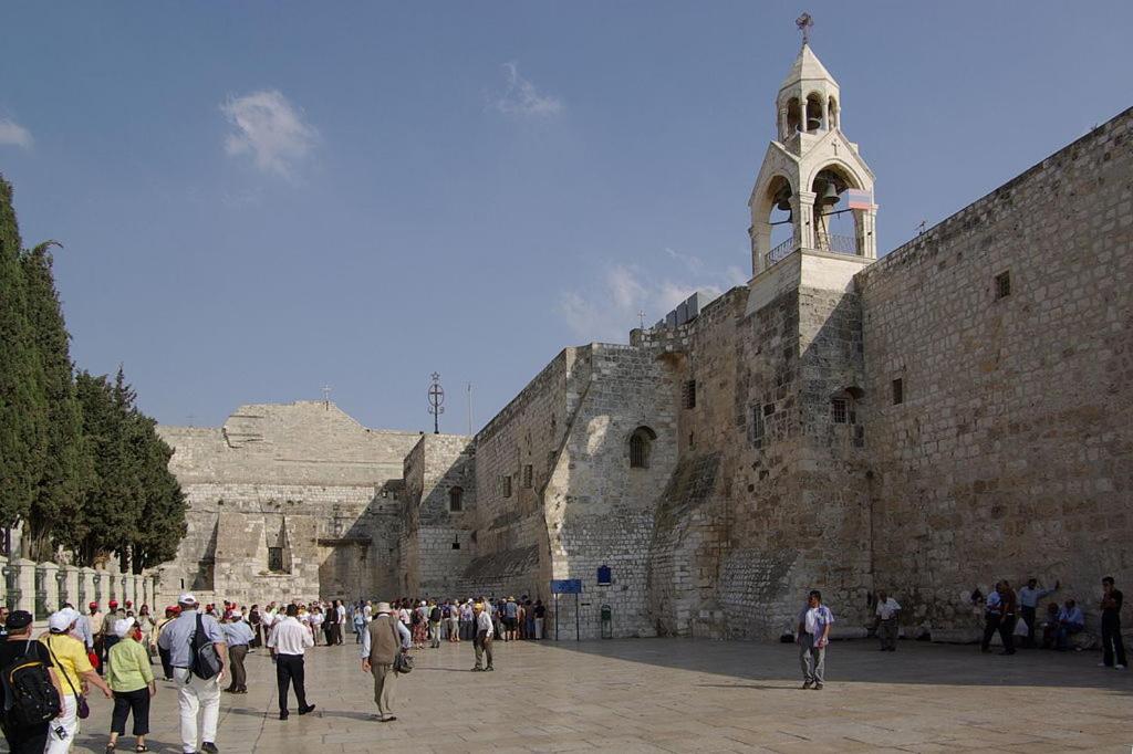 un grupo de personas caminando alrededor de un edificio de piedra en Sabrina Apartments, en Bethlehem