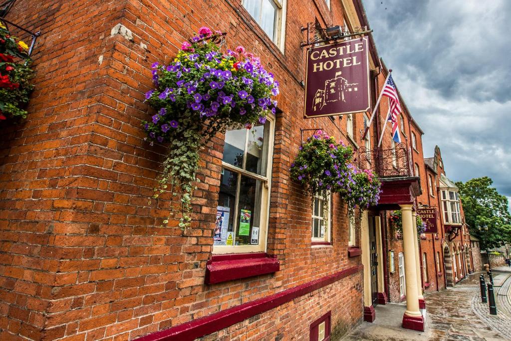 un edificio de ladrillo con flores a un lado. en Castle Hotel, en Tamworth