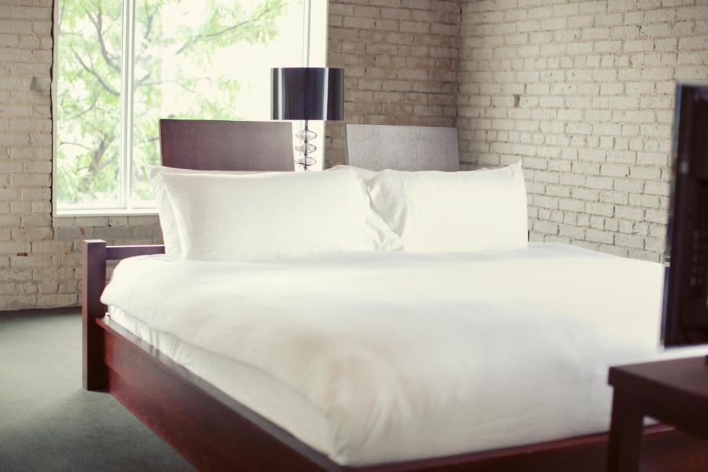 Una cama con sábanas blancas y almohadas en un dormitorio en Hotel Ocho en Toronto