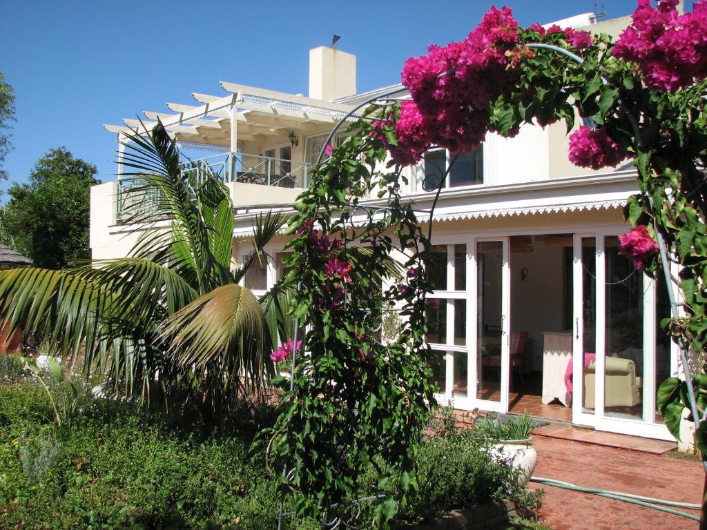 a white house with pink flowers in front of it at Constantia Lazy River in Cape Town