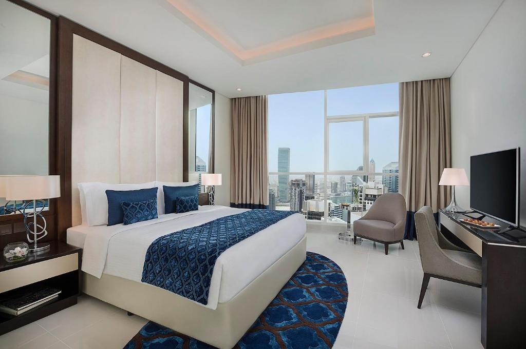 a bedroom with a bed and a desk and a computer at DAMAC Maison Distinction in Dubai