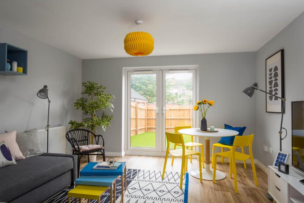 a living room with a table and yellow chairs at My Tetamu JLR Coventry House in Coventry