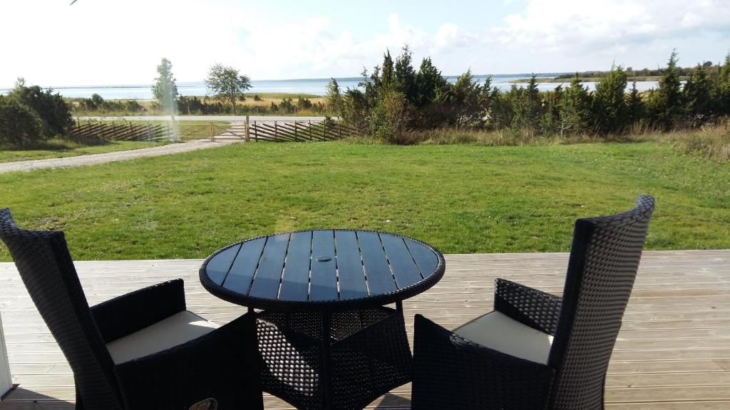 a table and chairs on a deck with a view of a field at Merekalda Puhkemaja in Orjaku