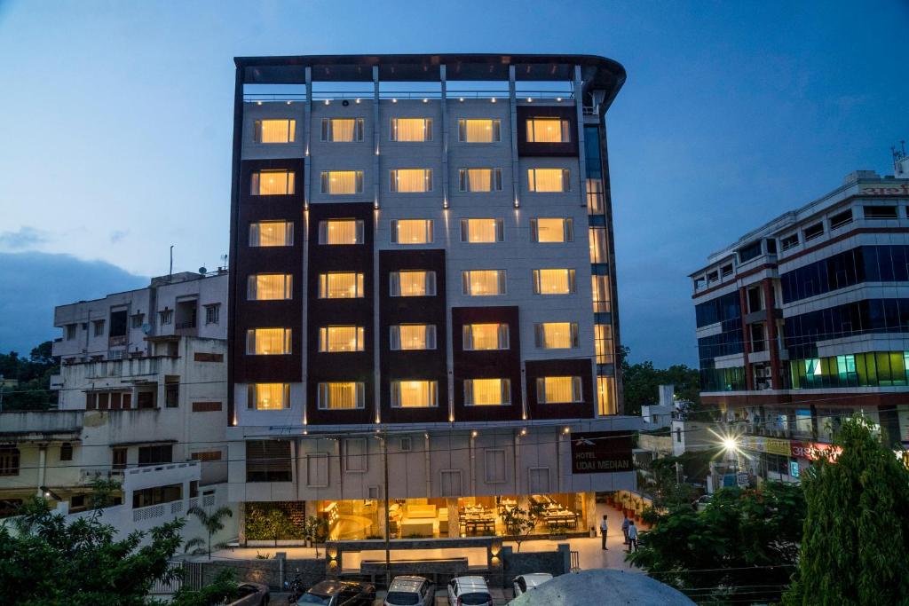 a tall building with illuminated windows in a city at Hotel Udai Median in Udaipur