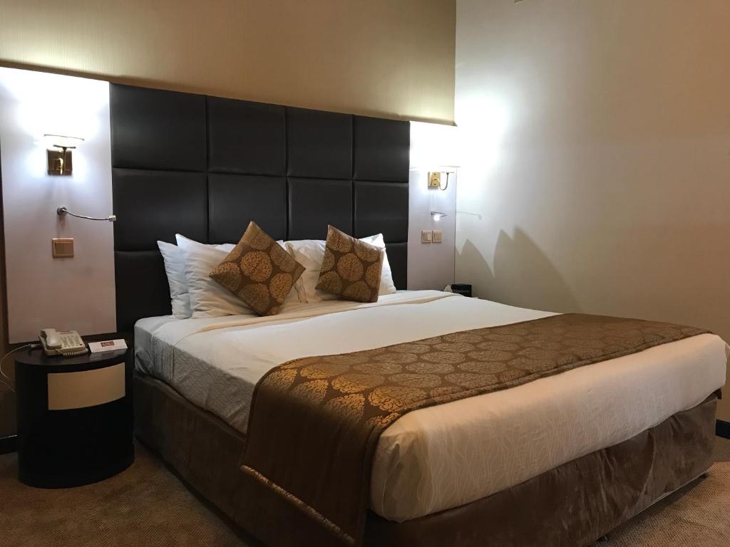 a bedroom with a large bed with a large headboard at THE PARK HOTEL Formerly Al Jawhara Gardens in Dubai