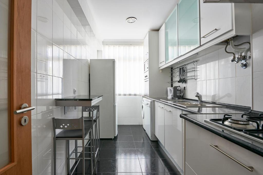 a kitchen with white appliances and a black floor at In Bed with Lisbon 4E in Amadora