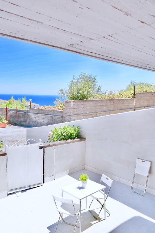 a patio with a table and chairs and the ocean at Villa Alba in Acitrezza