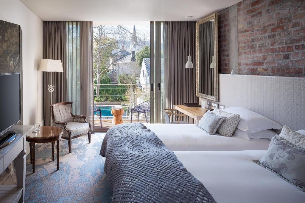 a hotel room with a bed and a large window at Oude Werf Hotel in Stellenbosch