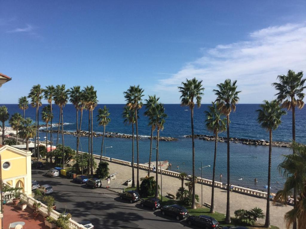 una calle con palmeras y el océano en B&b note di mare, en Imperia