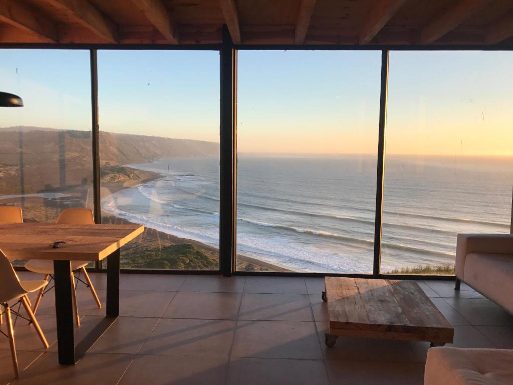 a living room with a table and a view of the ocean at Quadro Matanzas cabañas in Matanzas