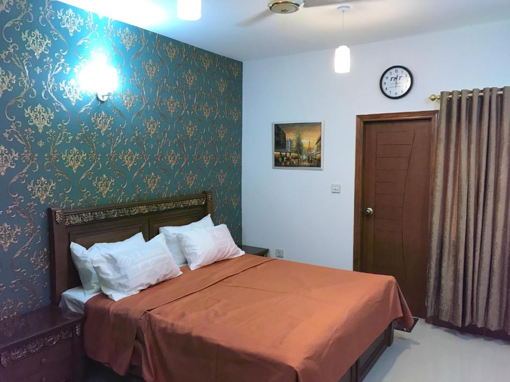 a bedroom with a bed and a clock on the wall at "Service Apartments Karachi" 3 Bed Javed Apartment in Karachi