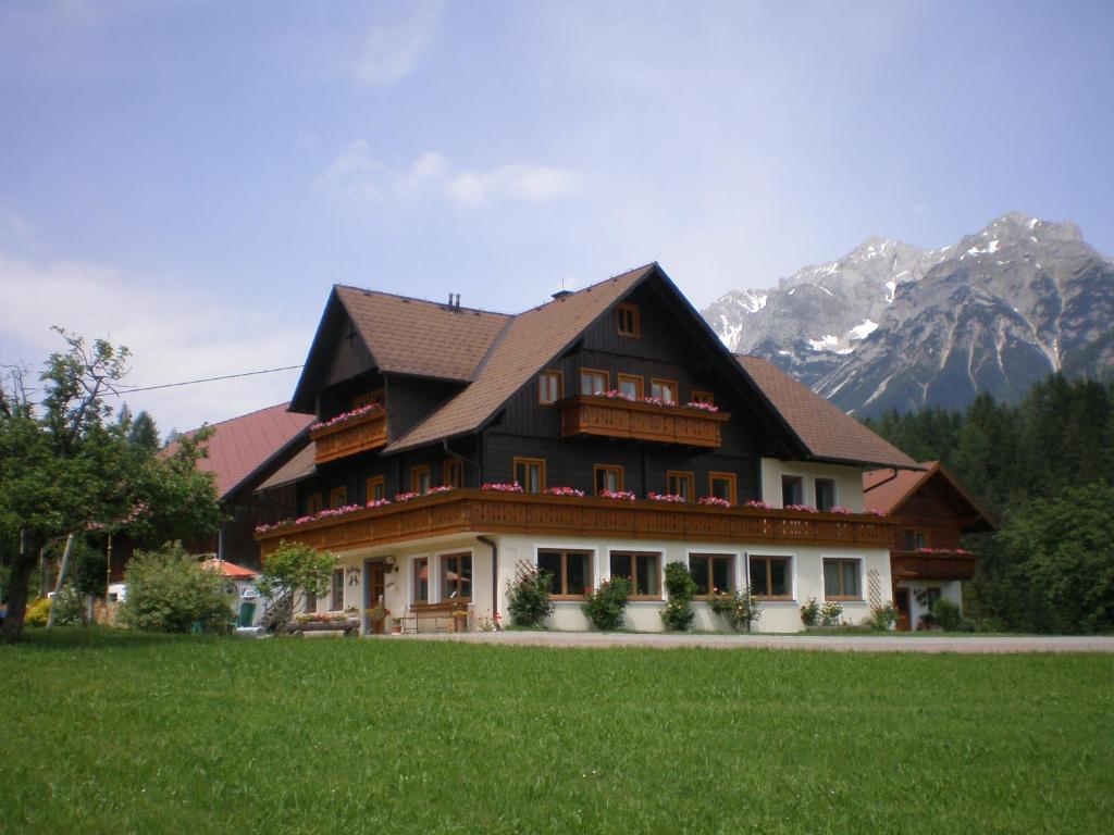 une grande maison avec des montagnes en arrière-plan dans l'établissement Pension Trillerhof, à Ramsau am Dachstein
