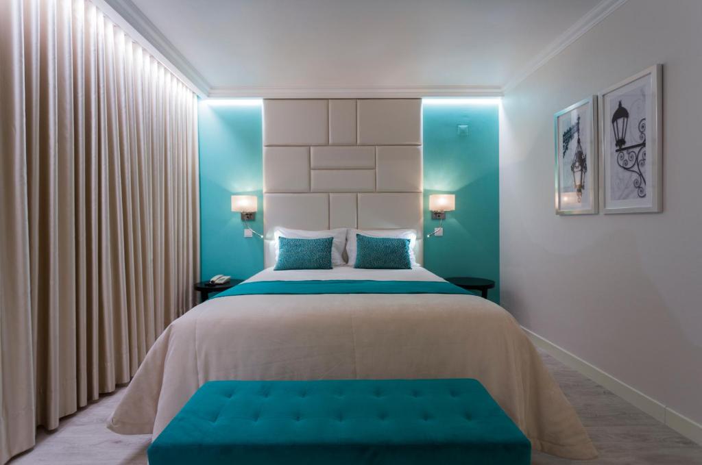 a bedroom with a large bed with blue accents at Josefa D`Obidos Hotel in Óbidos