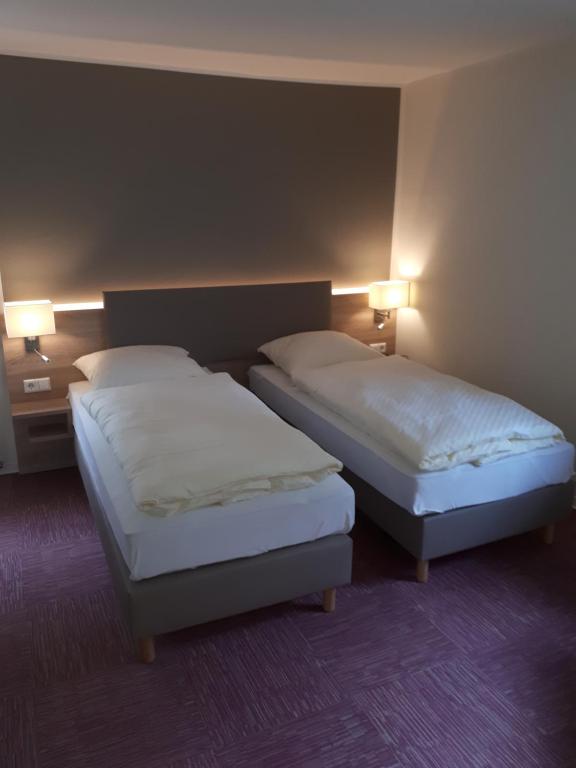 two beds in a hotel room with two lamps at Altdeutscher Hof Beckord in Gütersloh