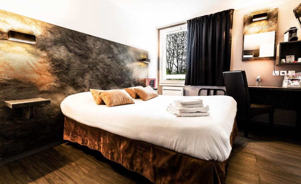 a bedroom with a large bed with towels on it at Logis Hotel Lons-le-Saunier - Restaurant Le Grill in Lons-le-Saunier