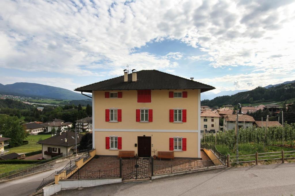 Casa da Aldo في Castelfondo: منزل كبير مع مصاريع حمراء على تلة