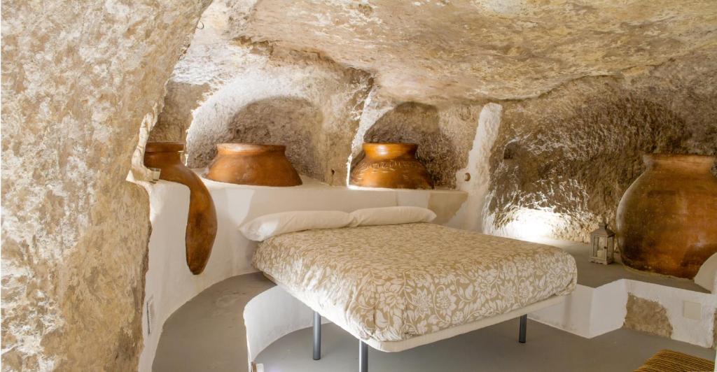 una habitación con un banco en una cueva con jarrones en Casa Cueva Las Tinajas de Naya, en Alcalá del Júcar