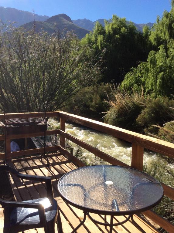 a table and chairs on a deck with a river at Cottages by the river in Rivadavia