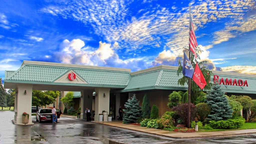 Um posto de gasolina com bandeiras americanas à frente. em Ramada by Wyndham Alpena em Alpena