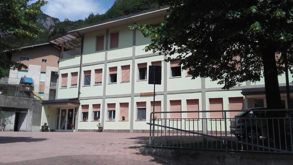 a large white building with pink doors and windows at Ostello Angolo Verde in Angolo Terme