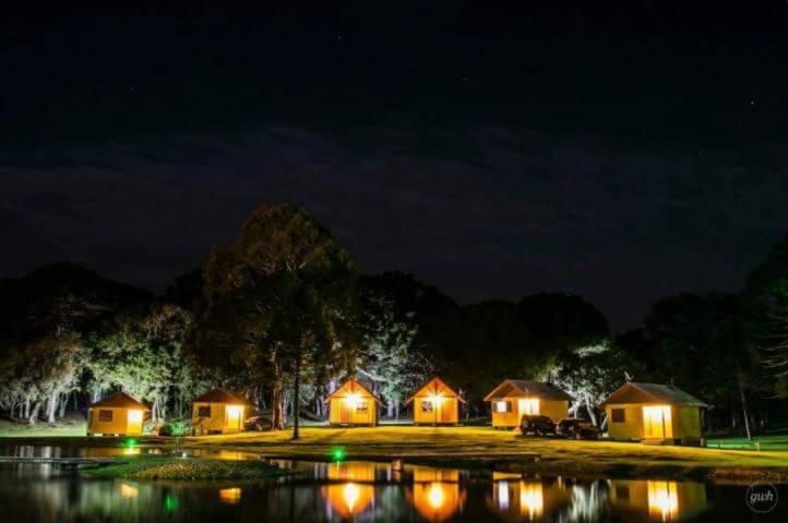 a group of lodges lit up at night at Hospedagem Encanto da Serra Rural in Cambará