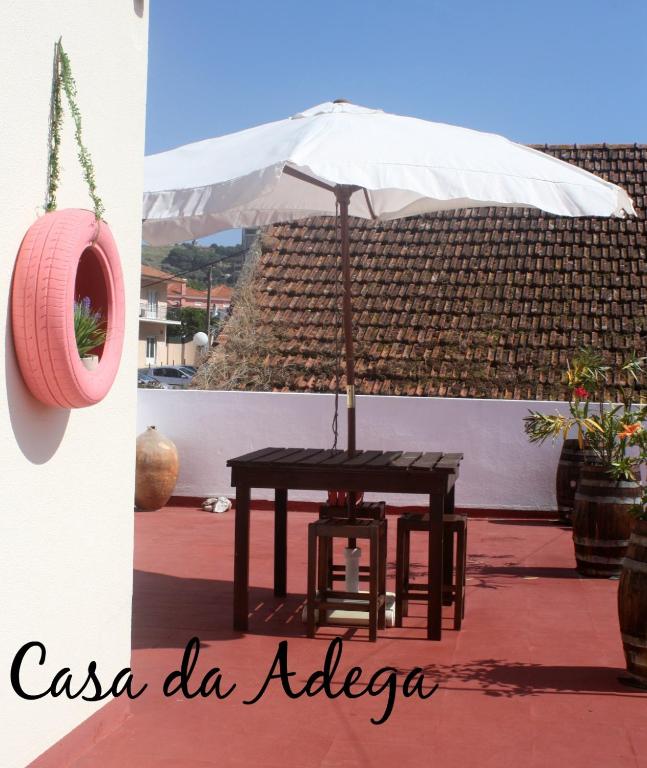 una mesa con una sombrilla blanca y una mesa con una silla en Casa da Adega, en Quinta do Anjo