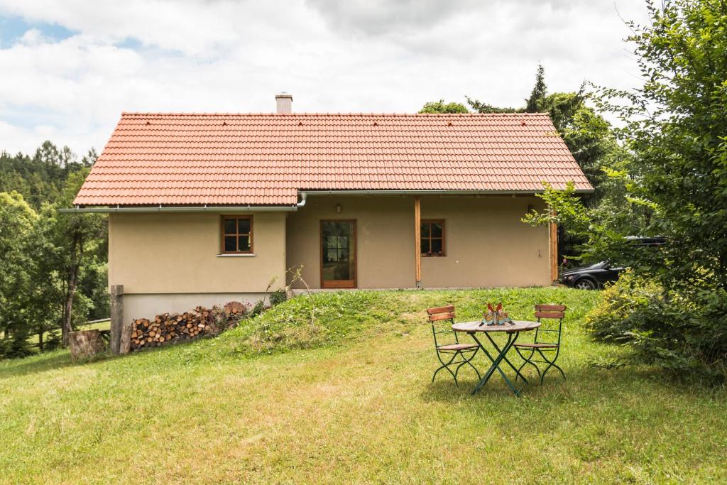 ein kleines weißes Haus mit einem Tisch im Hof in der Unterkunft Outline chata Svetla in Hartmanice