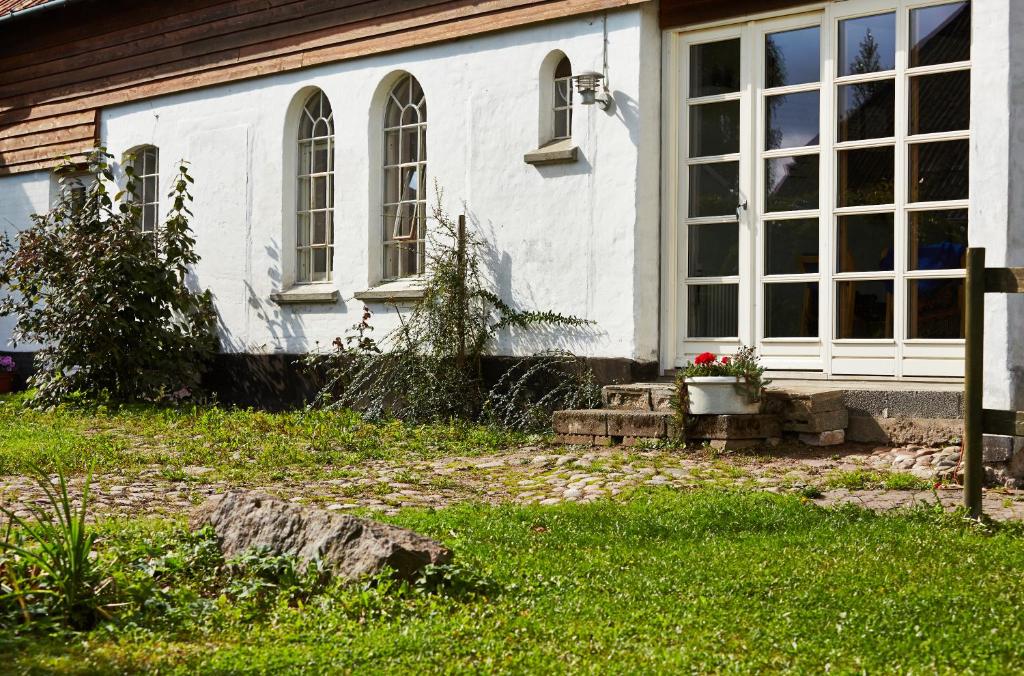 una casa blanca con ventanas y un banco en el patio en Rosenlund Bed & Breakfast en Skovsgårde